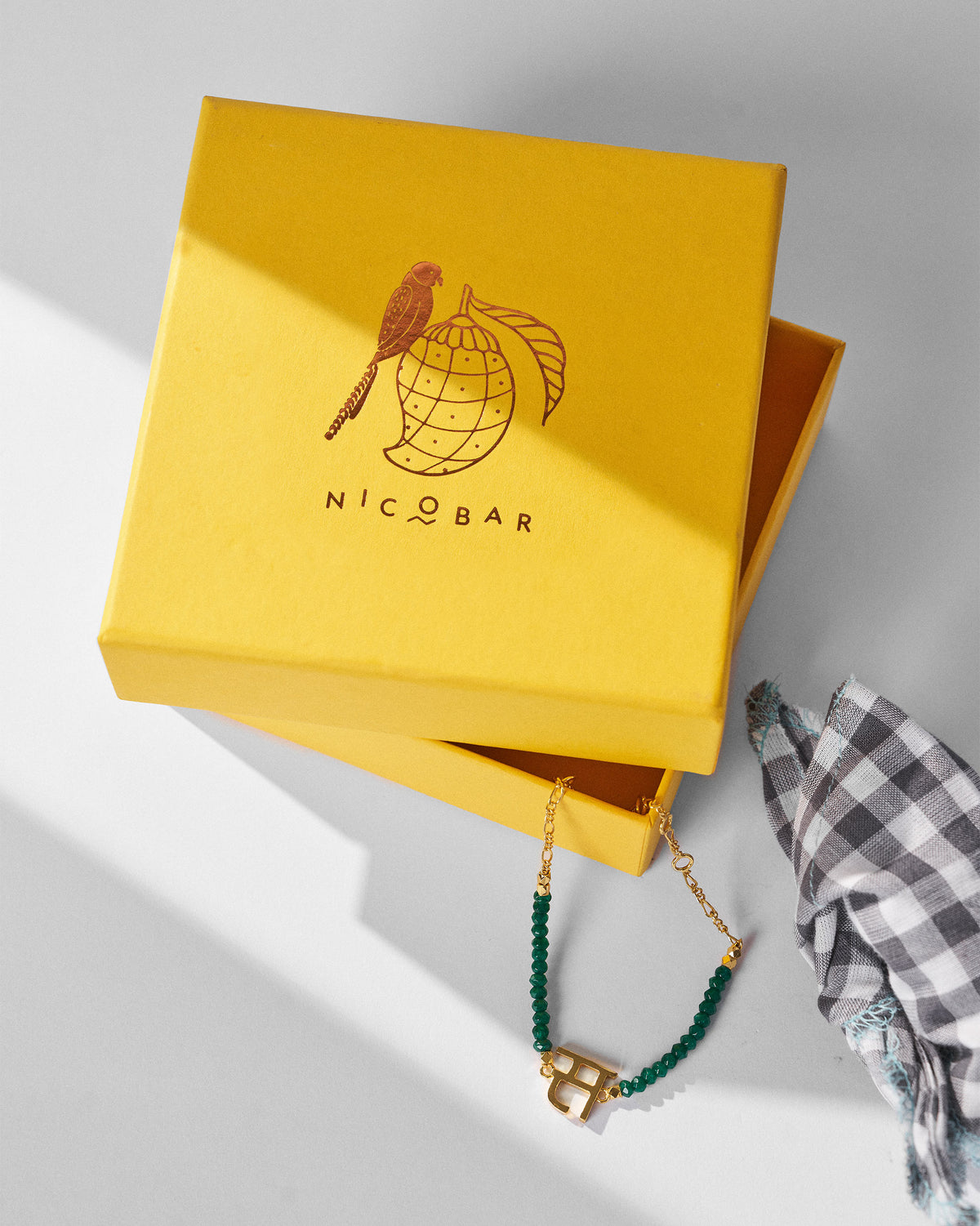 Akshar Bracelet (S) - Gold resting beside a yellow gift box.