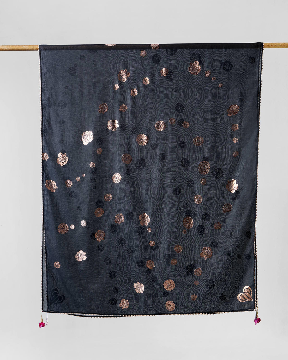 Close-up of a pink sequin tassel on black fabric with copper motifs.