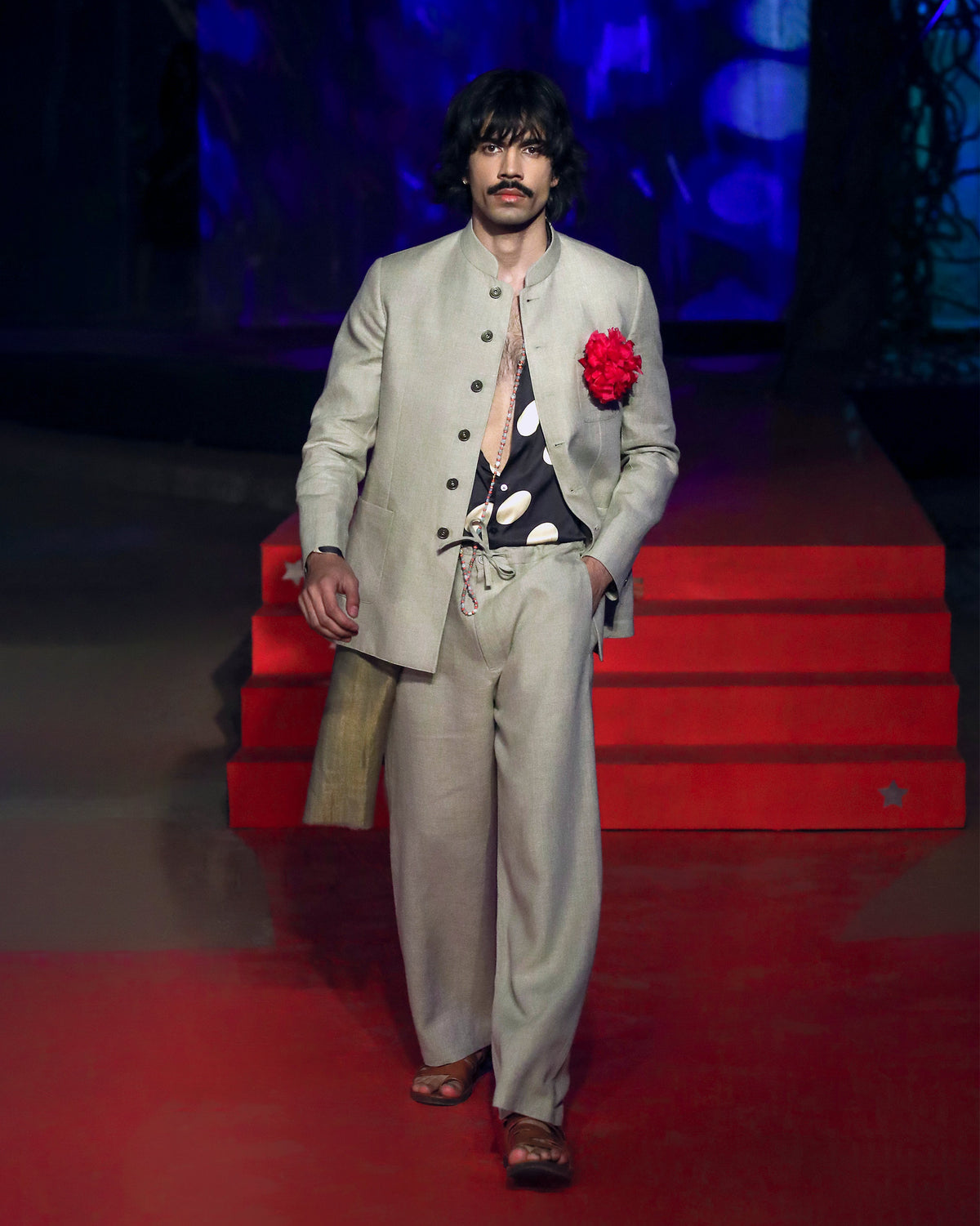 Person wearing a beige Tahr bandhgala with a red flower accent.