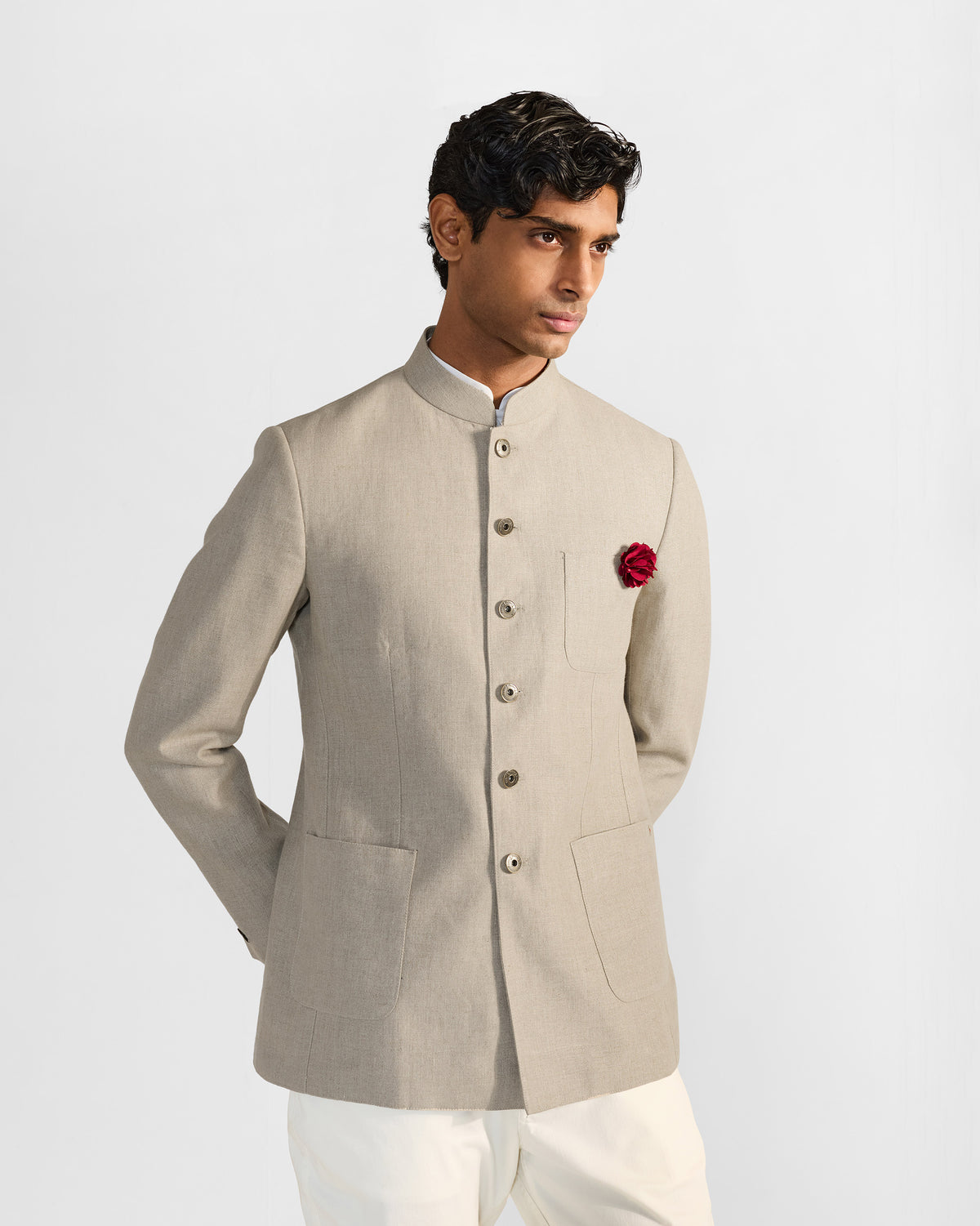 Person wearing a beige Tahr bandhgala with a mandarin collar and red floral accent.
