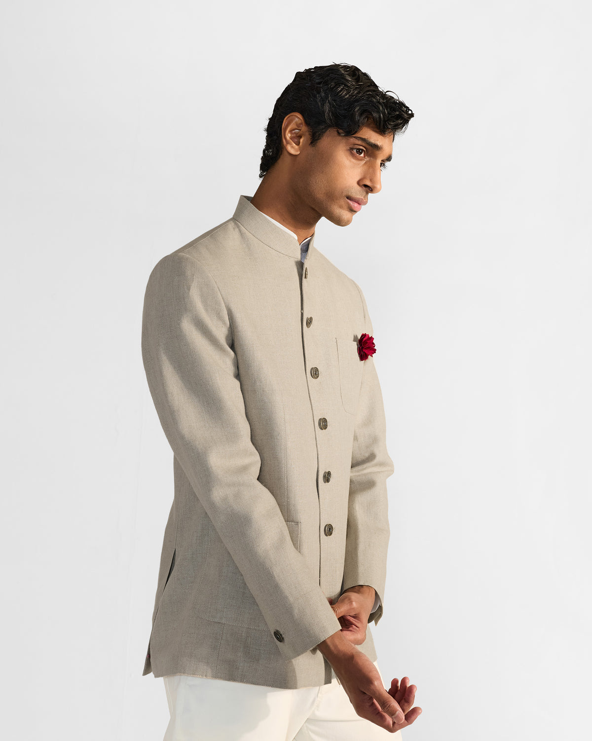Side view of a beige Tahr bandhgala with dark buttons and a red rose accent.