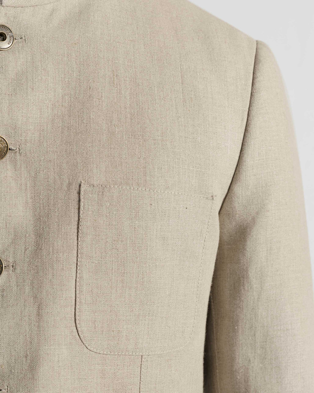 Close-up of the chest pocket and brass buttons on a beige Tahr bandhgala.
