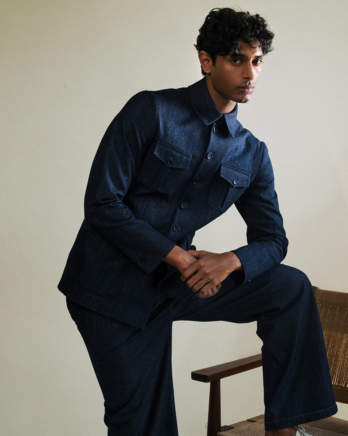 Person wearing a buttoned indigo denim Ibex travel jacket with chest pockets.
