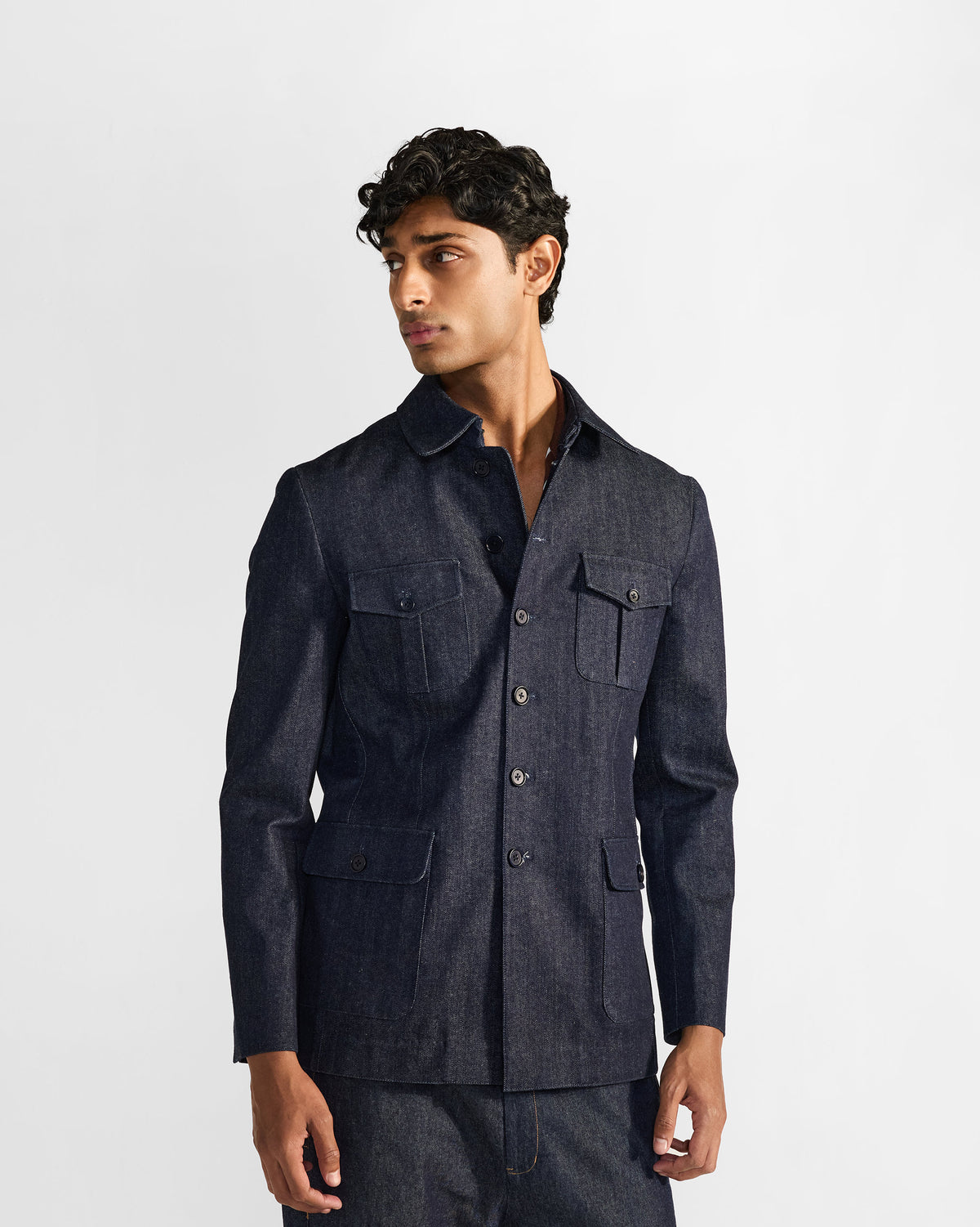 Person wearing an indigo denim Ibex travel jacket with four flapped pockets.