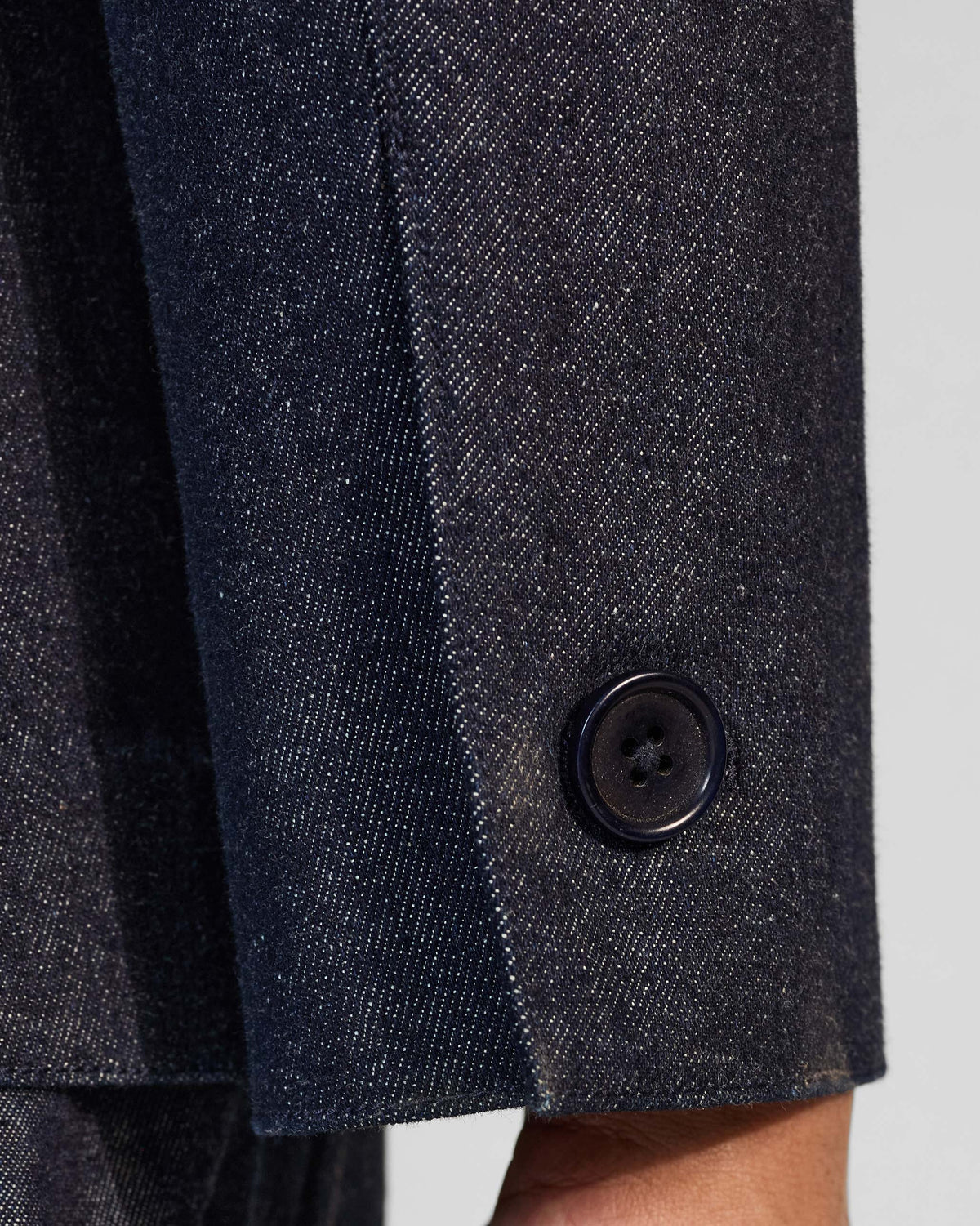 Close-up of the buttoned cuff on an indigo denim Ibex travel jacket.