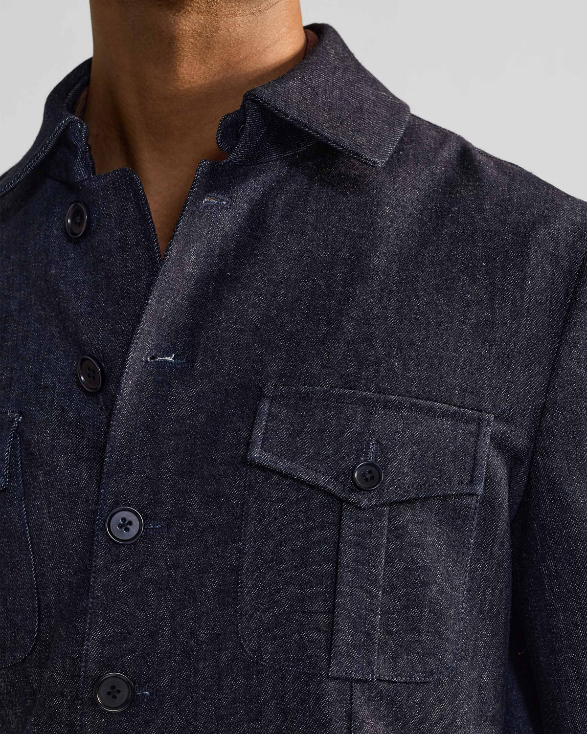 Close-up of the collar and flapped chest pocket on an indigo Ibex travel jacket.