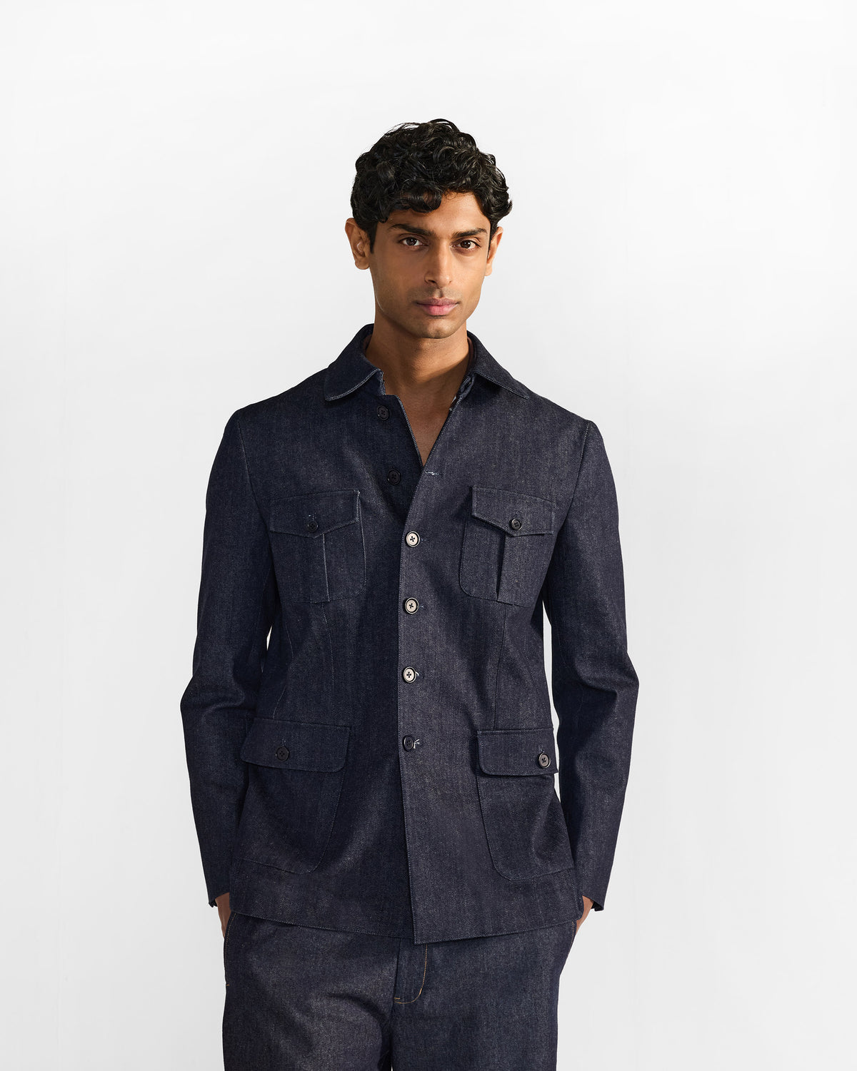 Person wearing an indigo denim Ibex travel jacket with four utility pockets.