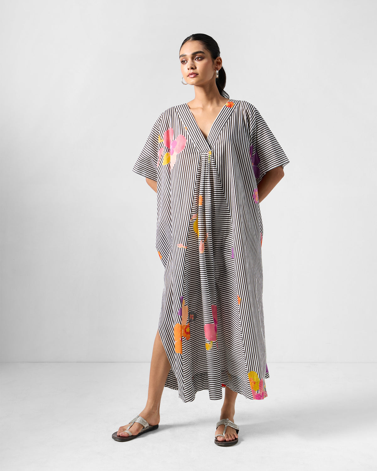 Person wearing a striped Noa kaftan with colourful floral prints.