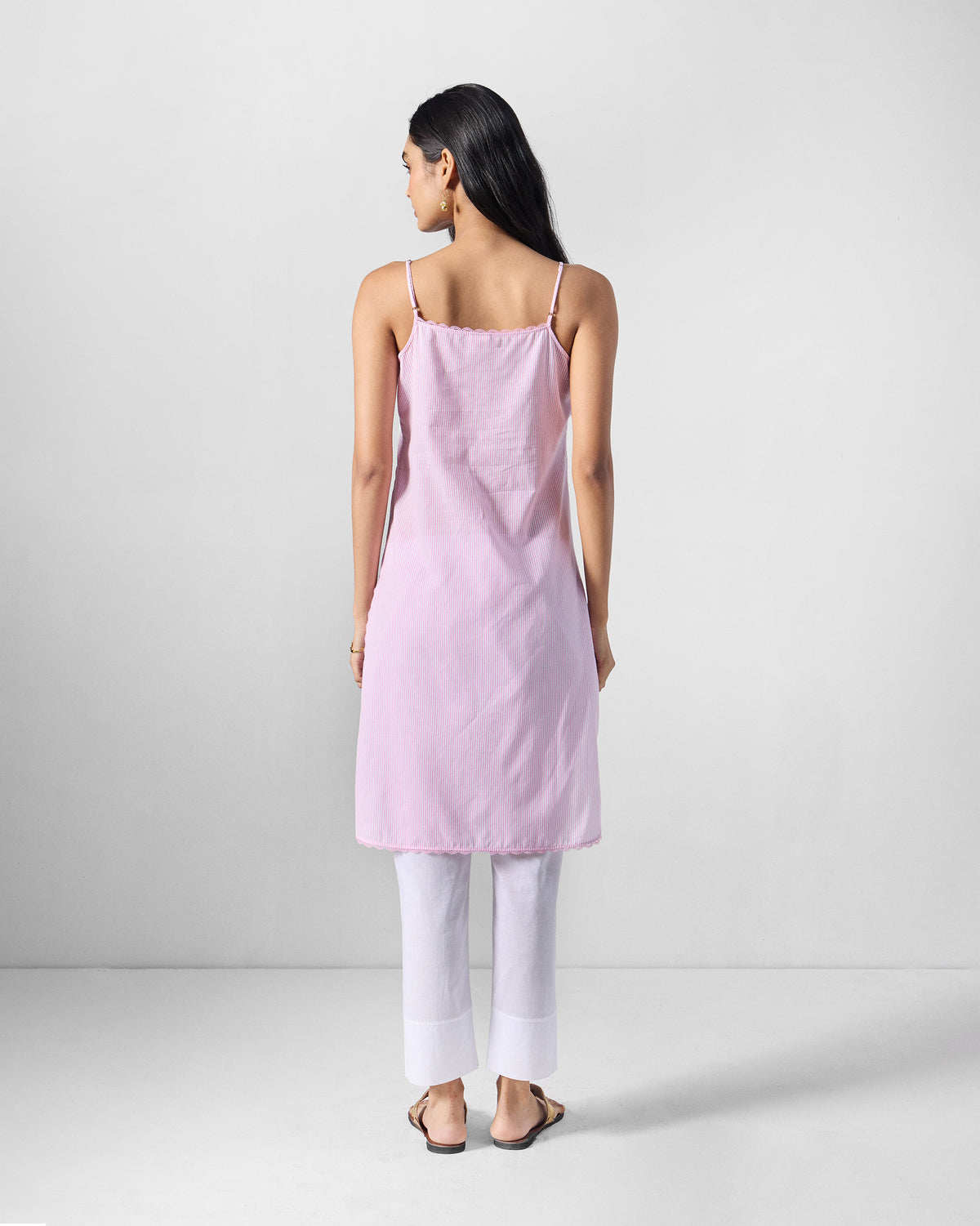 Back of a pink Sinatra slip with thin straps worn by a person.