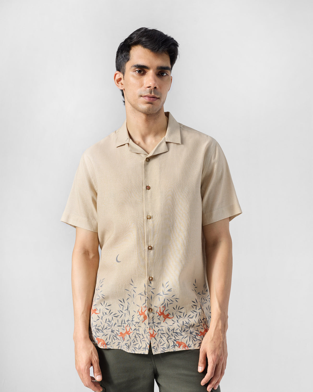 Person wearing a beige Delta shirt with a monkey foliage hem print.