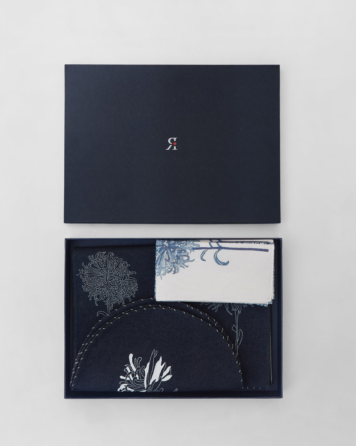 Open Chandramallika gift box filled with navy and white floral table linens.