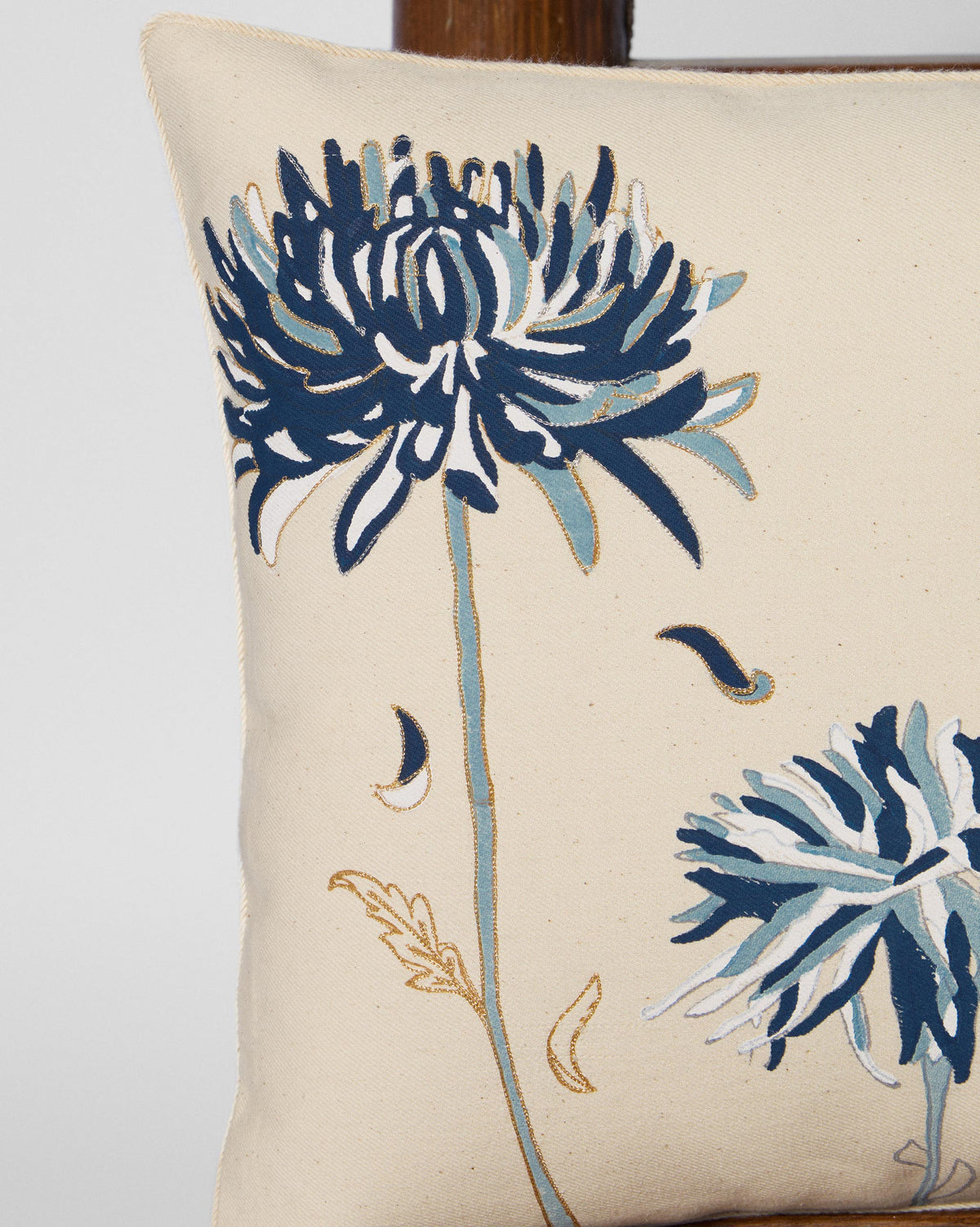 Close-up of a Guldaudi cushion showing blue flower prints on cream fabric.