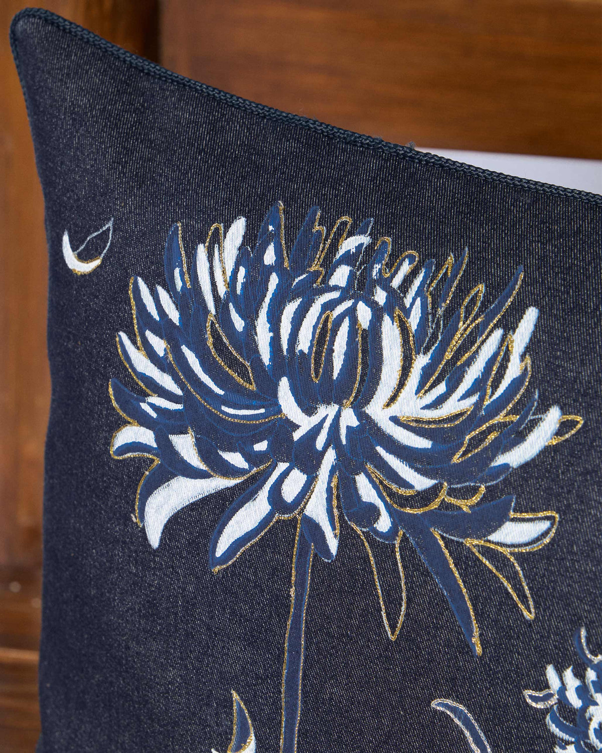 Close-up of blue and white flower heads with gold outlines on a Neelakurinji cushion.