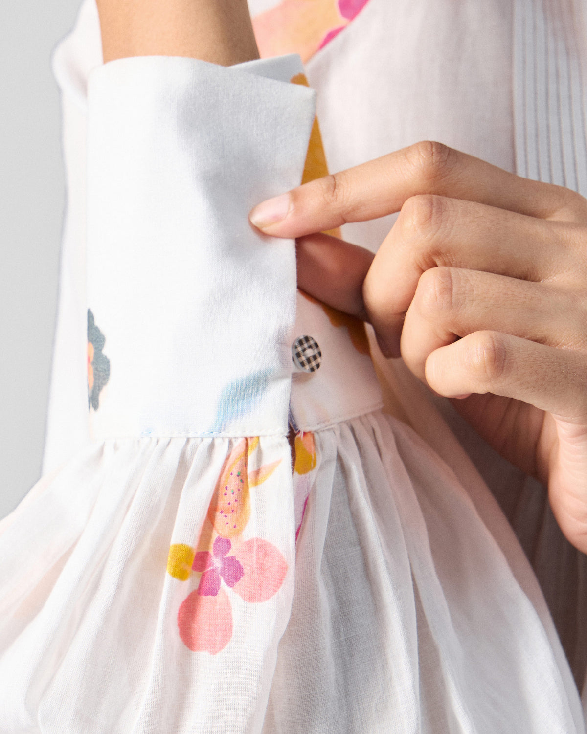 Close-up of Flutter Blouse cuff with a checkered button on floral sleeve.