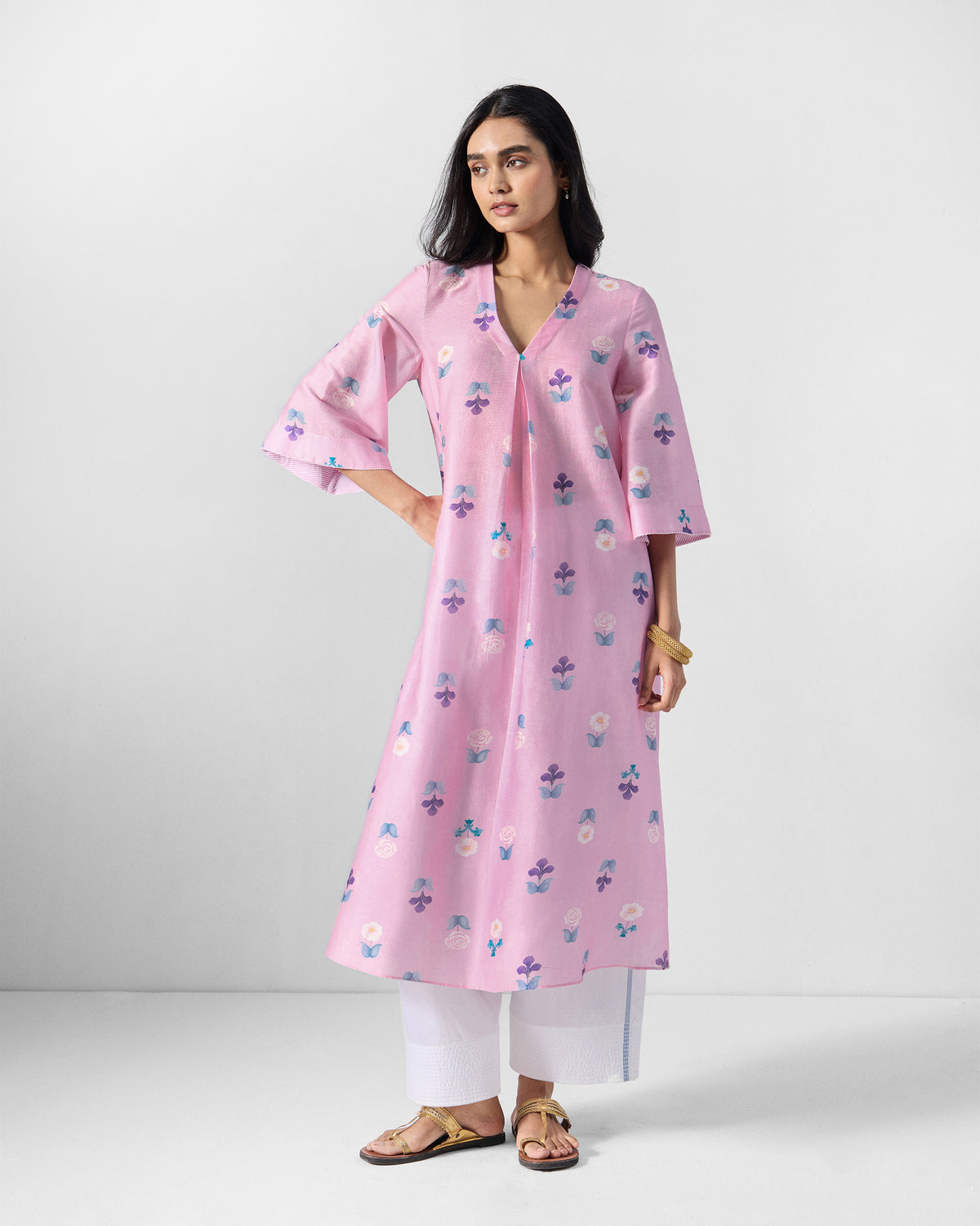 Person wearing a soft pink floral Hera Kurta with a V-neck and flared sleeves.