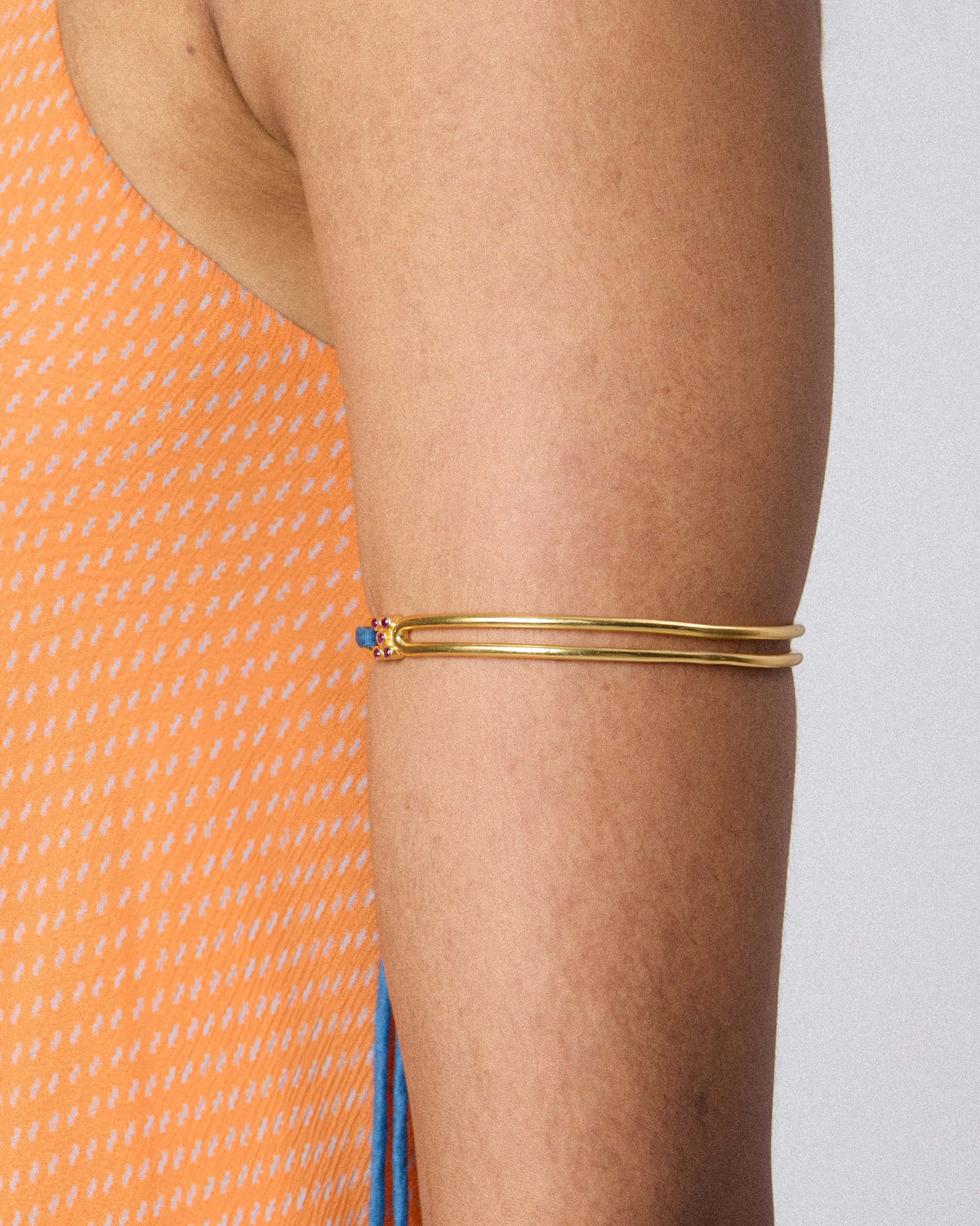Gold baju bandh worn as a double-band armlet on the upper arm.