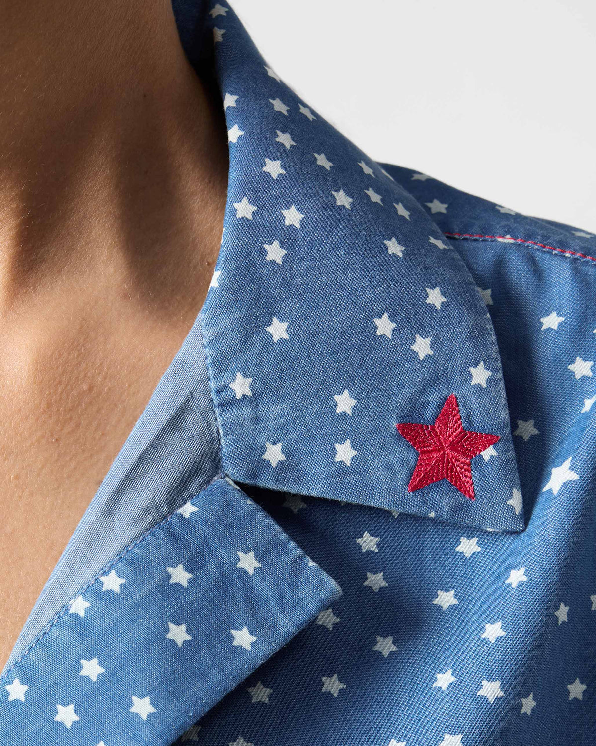 Close-up of a blue Swing top showing a red embroidered star on the collar.