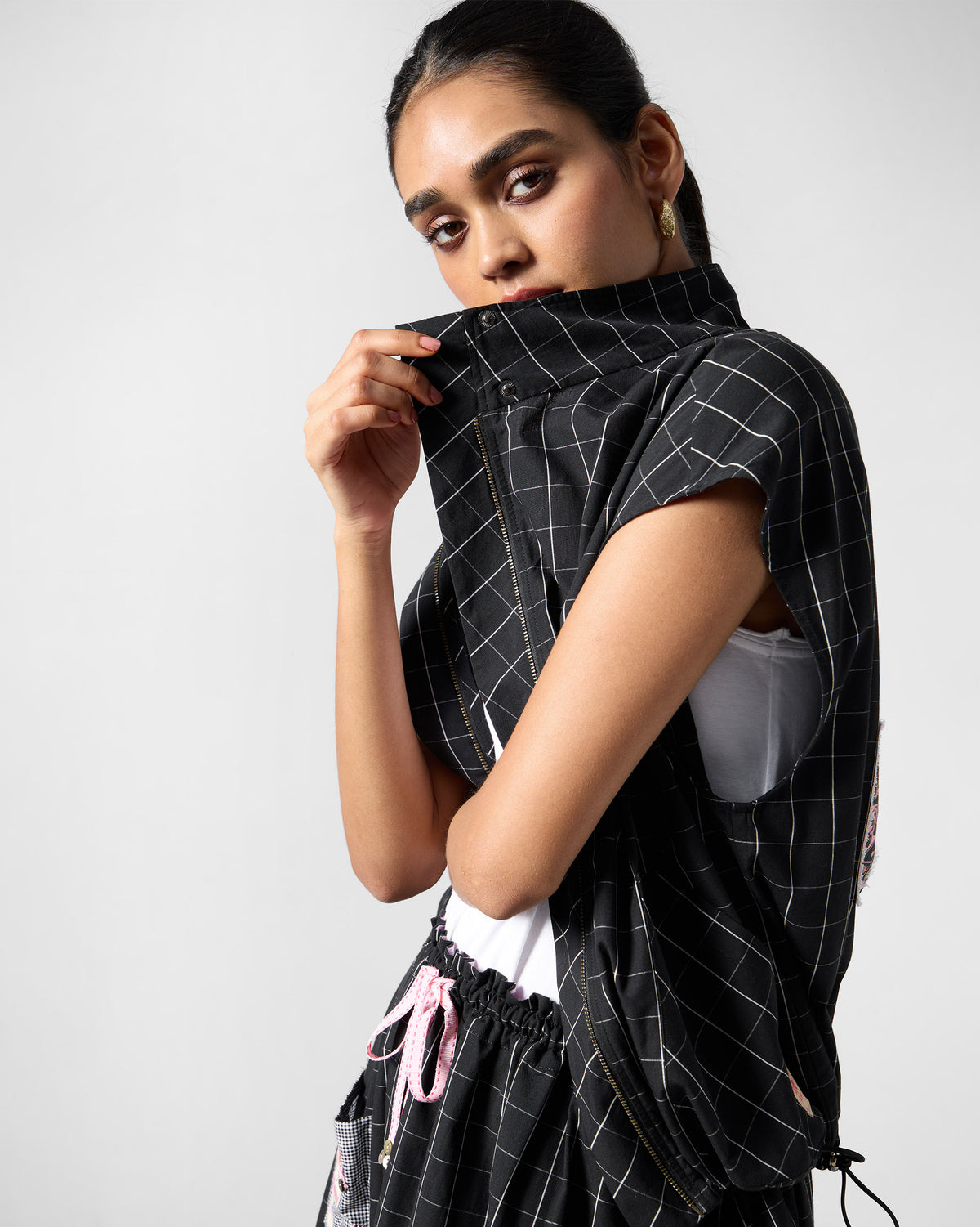 Person wearing a zipped black-and-white checked Renai top with a high collar.