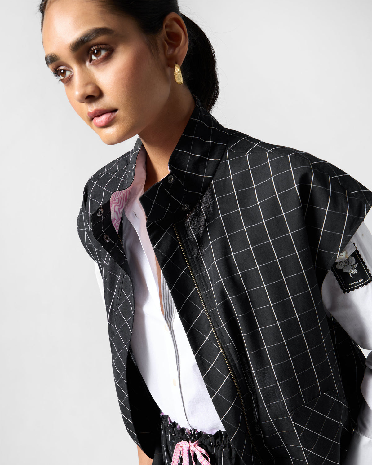 Close-up of the zipper and pink lining on a black-and-white checked Renai top.