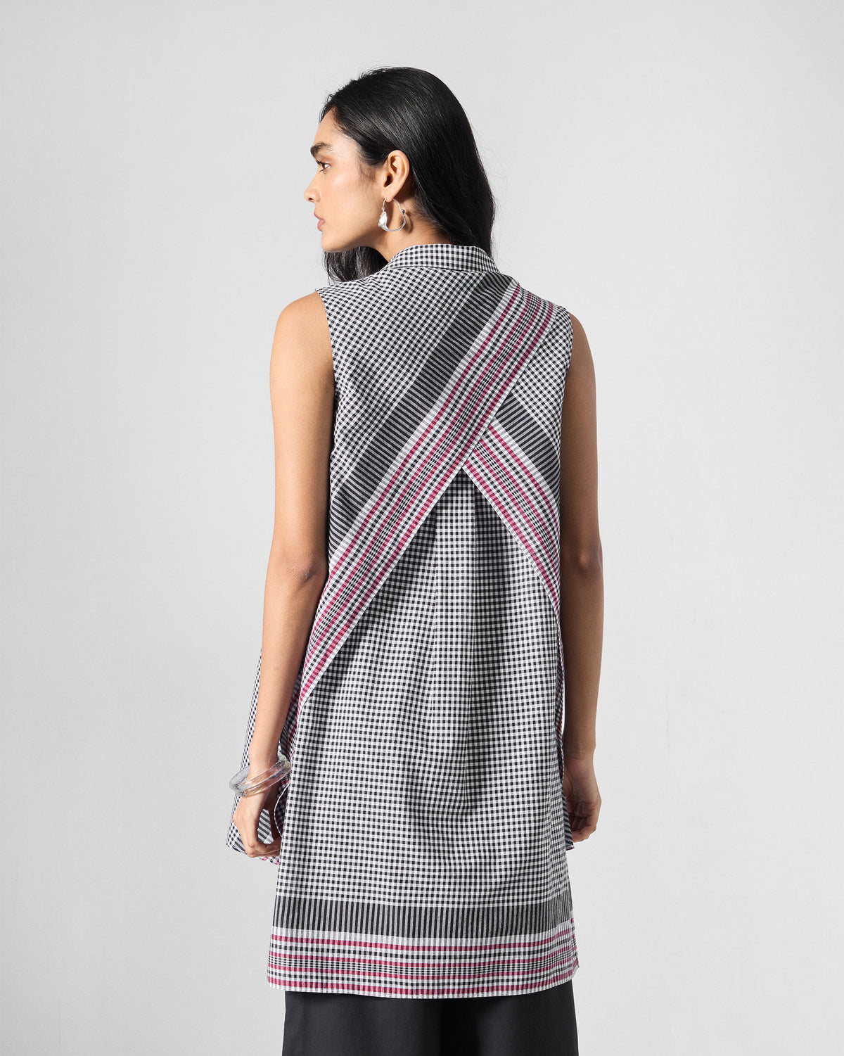 Back of a black and white check tunic with crossed panels and striped borders.