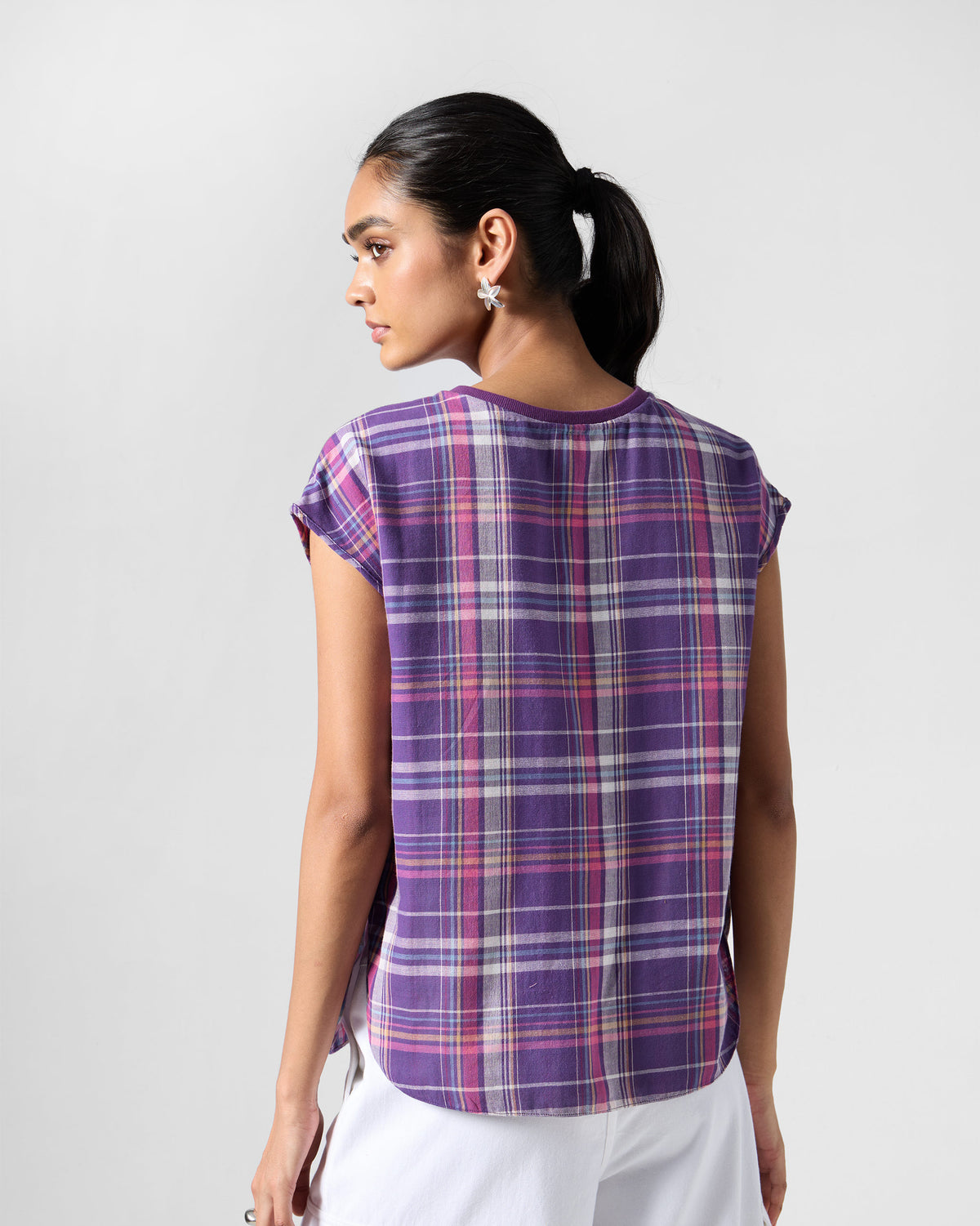 Back of a purple plaid Flow top with a curved shirt-tail hem.