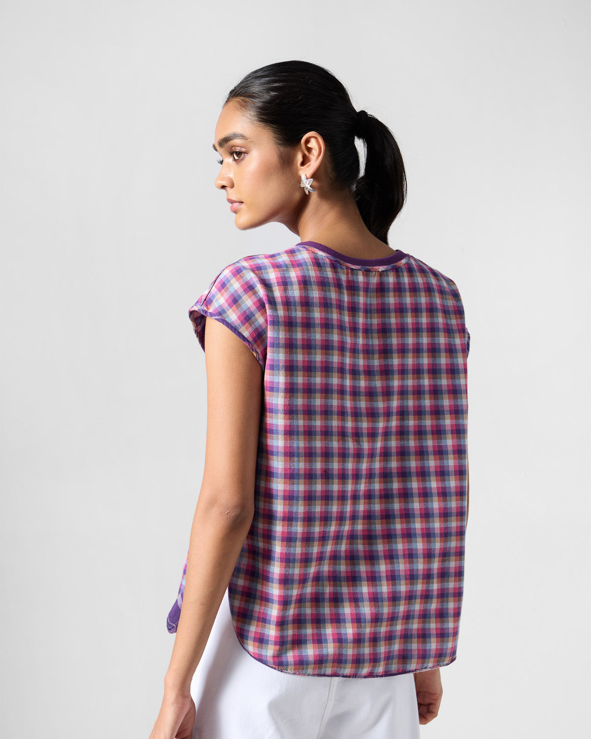Back of a purple and pink check Flow top with a curved hem.