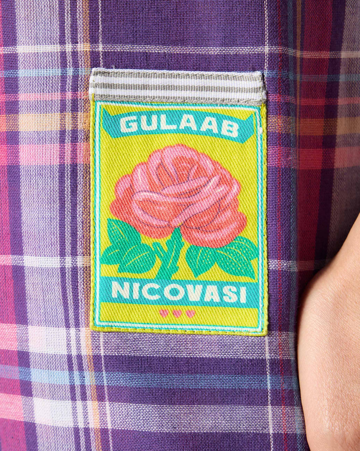 Close-up of the green rose patch on a purple check Flow top.