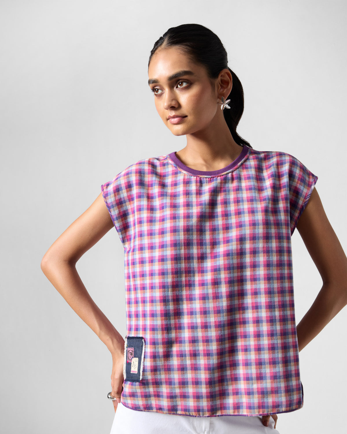 Person wearing a purple check Flow top with a denim hem patch.