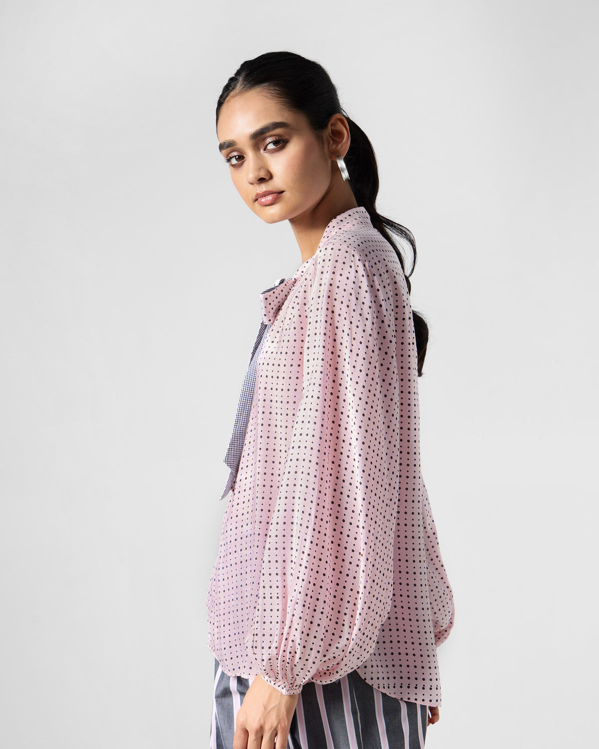 Side view of a pink polka-dot Spring tie shirt with balloon sleeves.