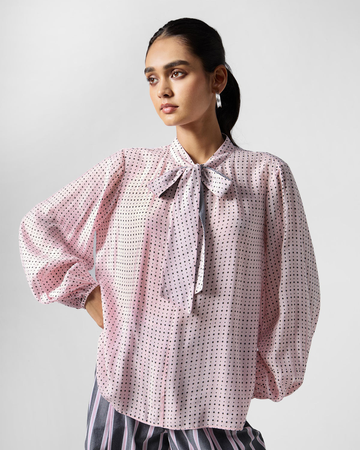 Person wearing a pink polka-dot Spring tie shirt with a pussy-bow.