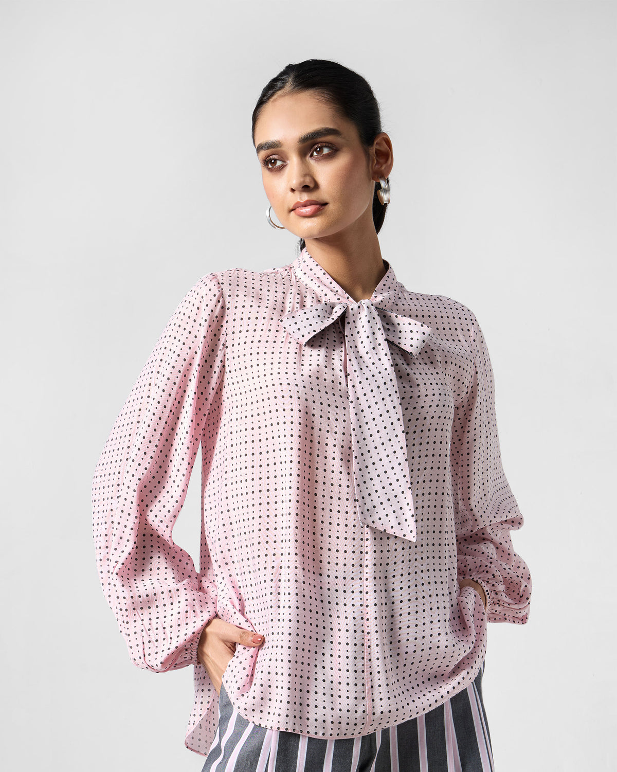 Person wearing a pink polka-dot Spring tie shirt with a pussy-bow.