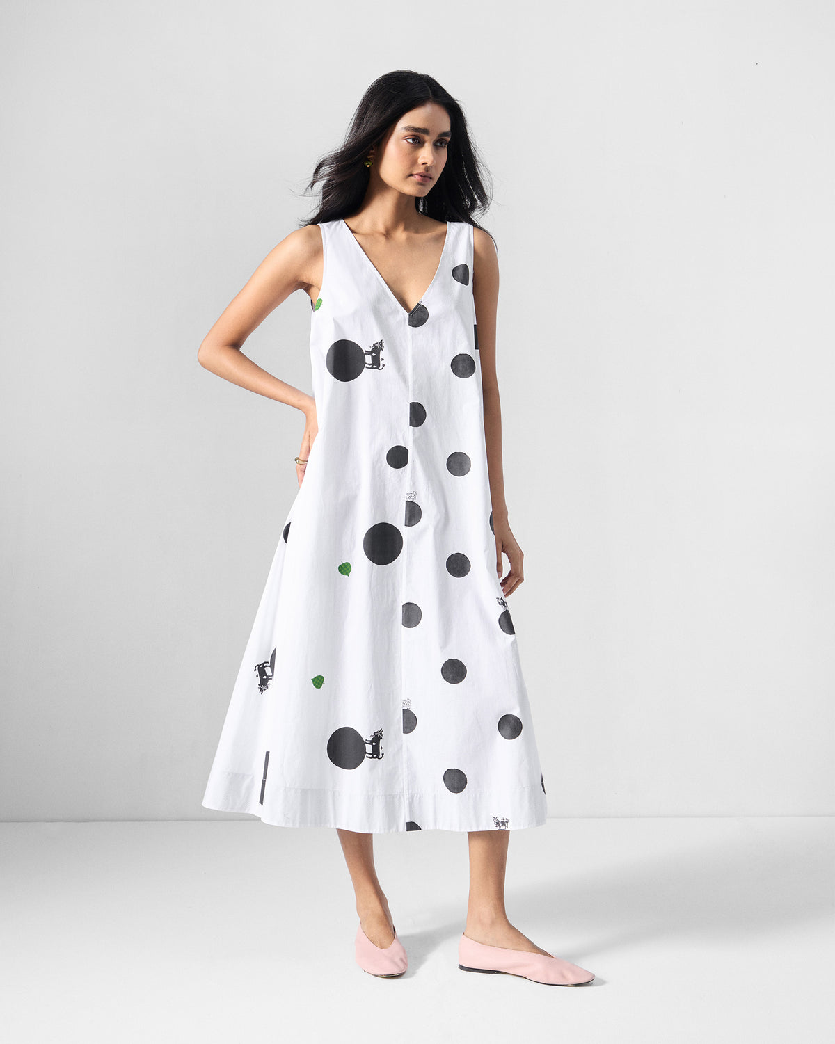 Person wearing a white sleeveless midi dress with black polka dots.