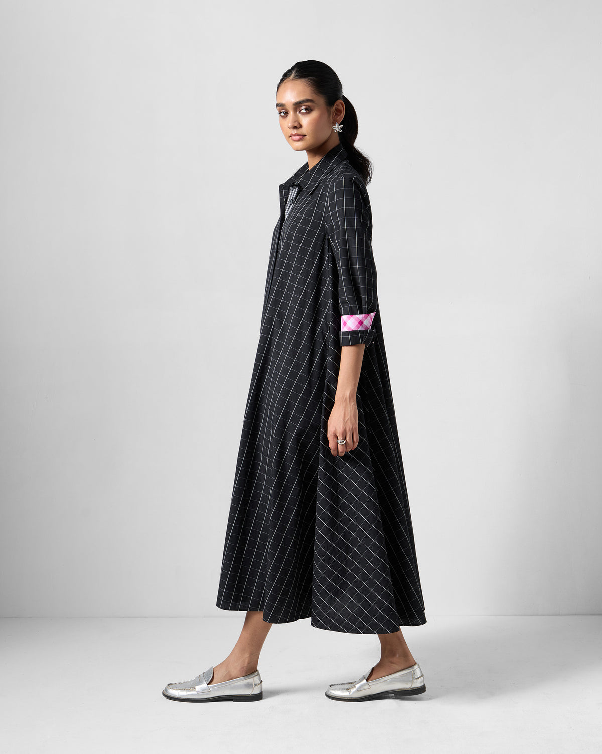 Side view of a black check Spiti shirt dress with a pink cuff.