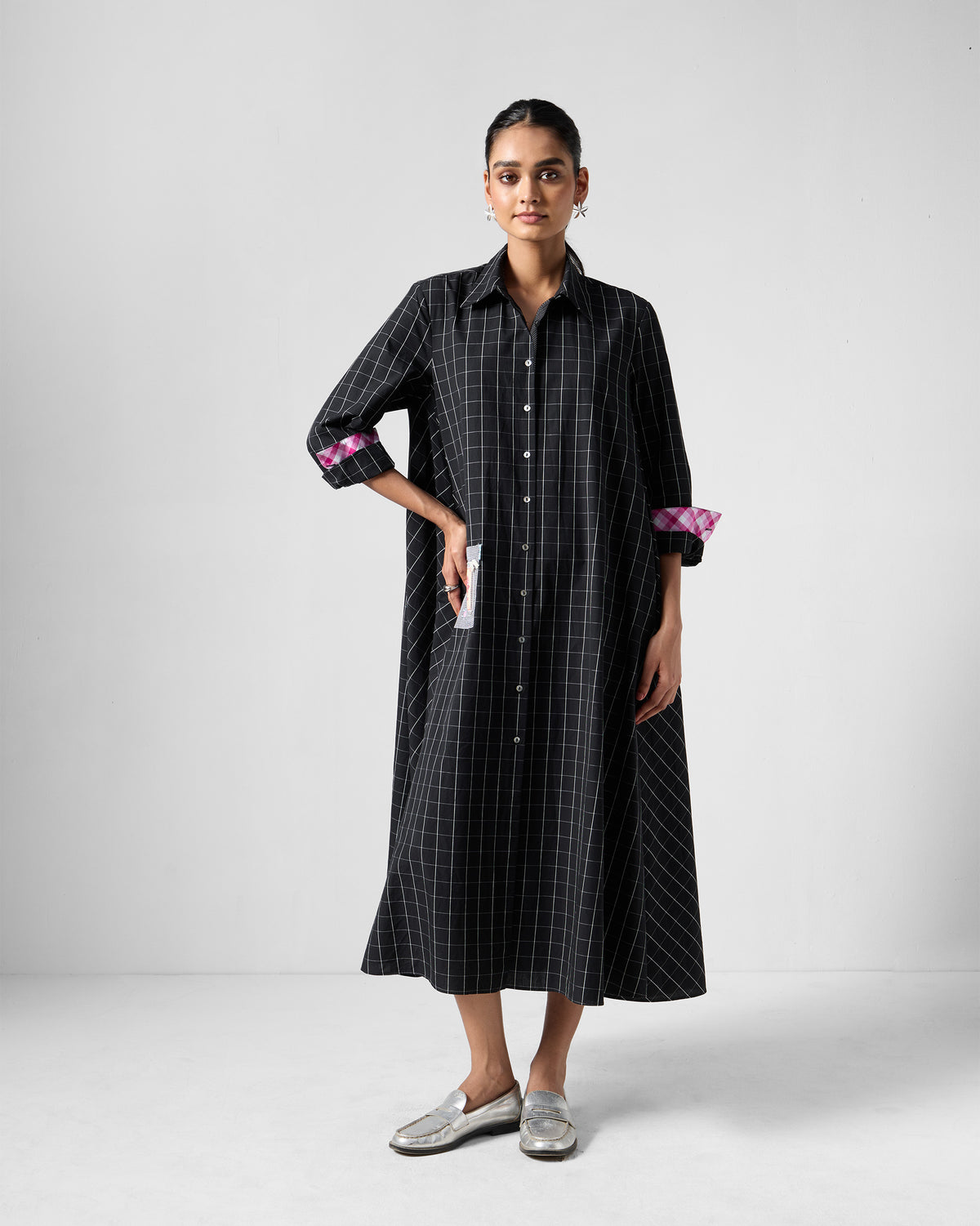 Person wearing a black check Spiti shirt dress with pink cuffs.