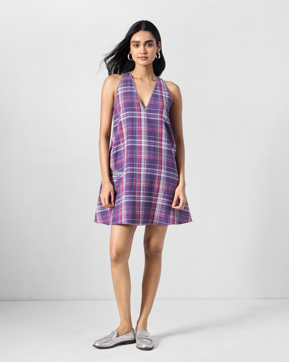 Person wearing a sleeveless purple check Daye reversible dress.