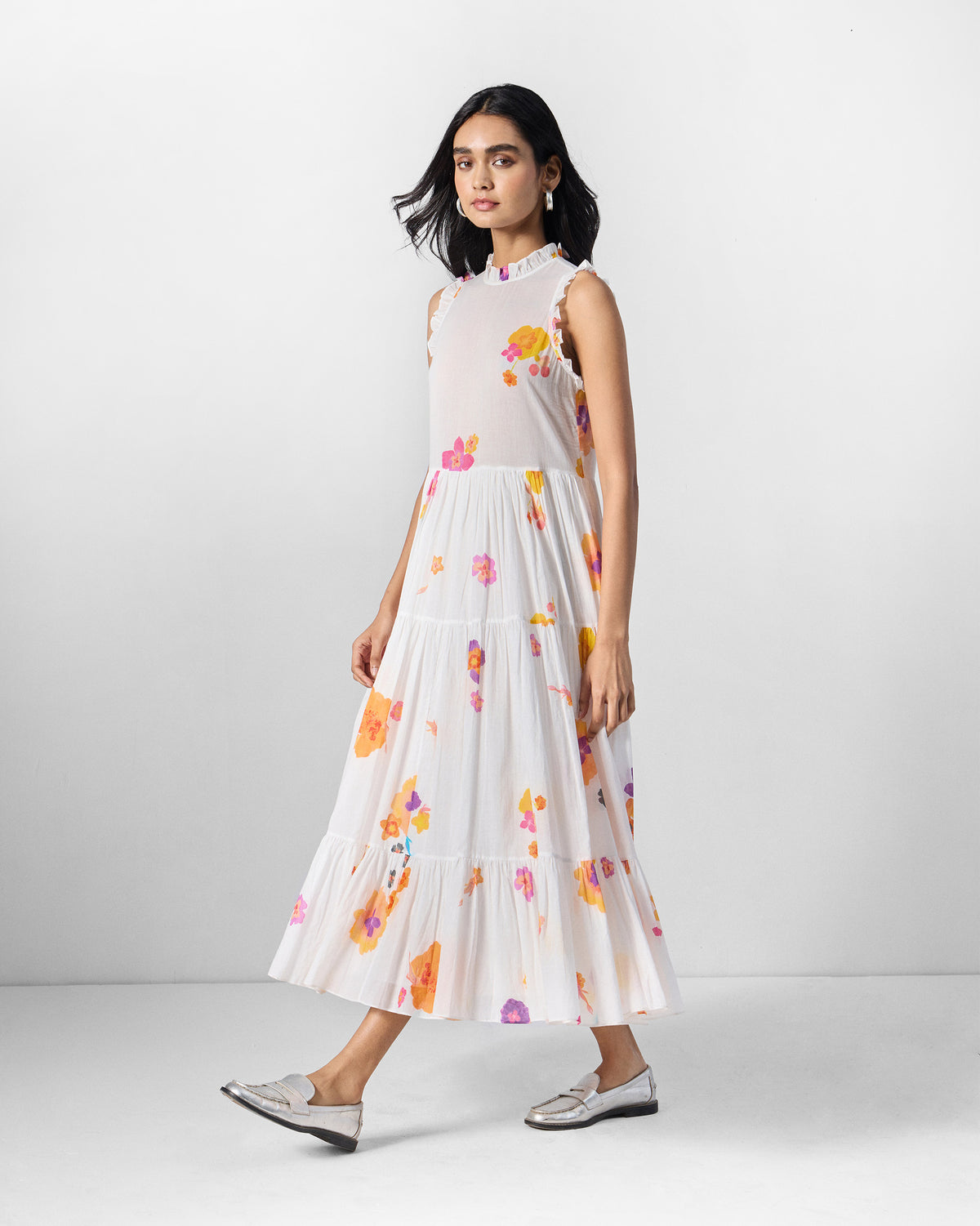 Person wearing an ivory Reah dress with a tiered skirt and floral print.