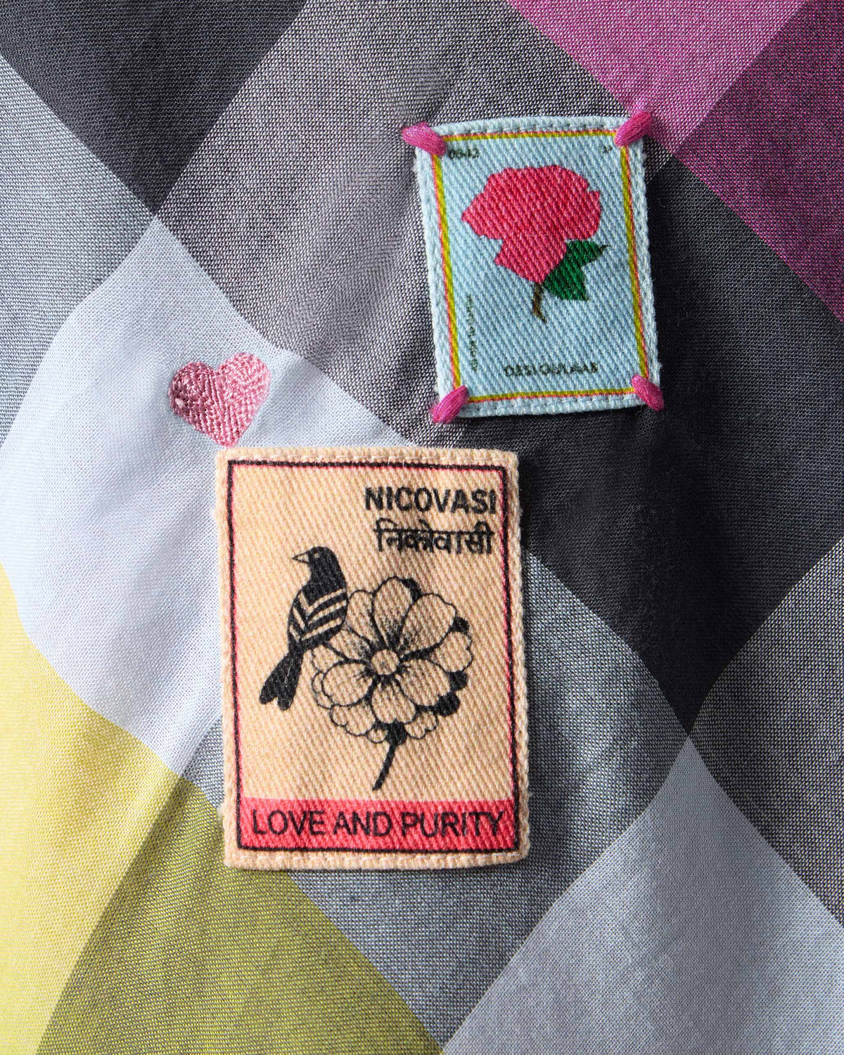 Close-up of Nicovasi and flower patches on a multicolour check Areva A-Line Dress.