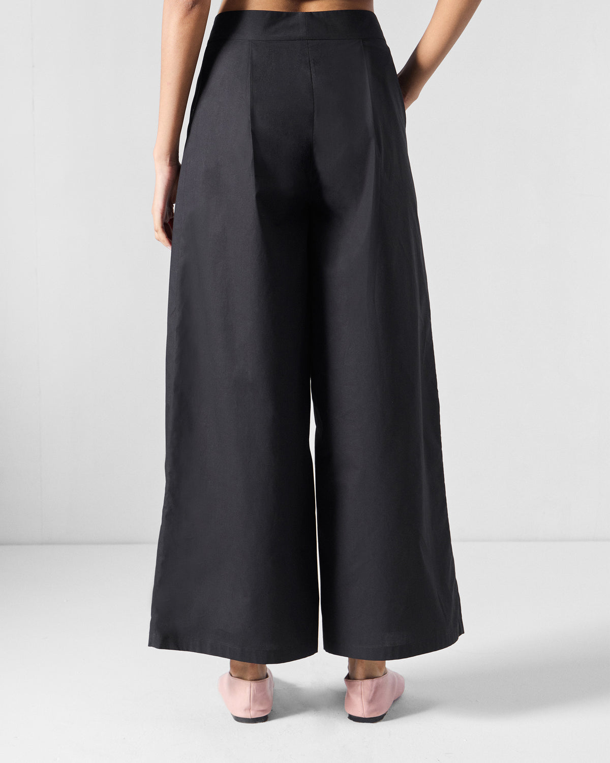 Back of black wide-leg Bank pants with shaping darts at the waist.