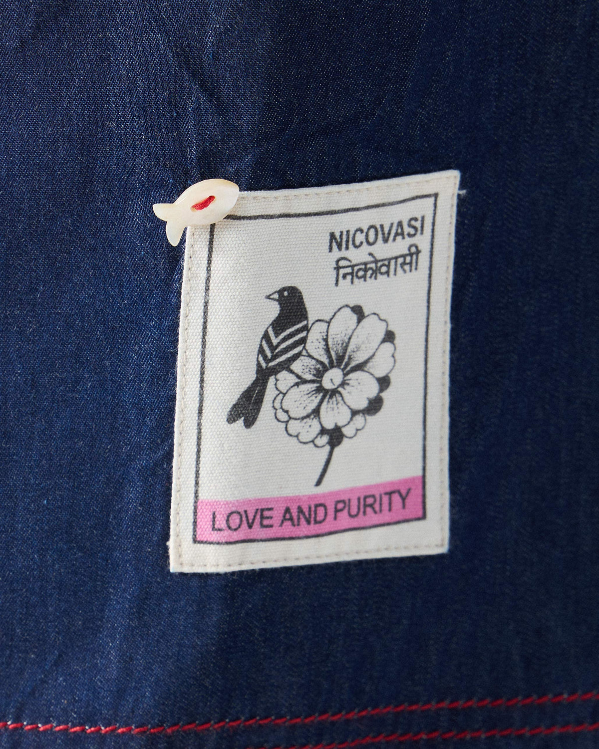 Close-up of a bird label and fish button on blue Ella culottes.