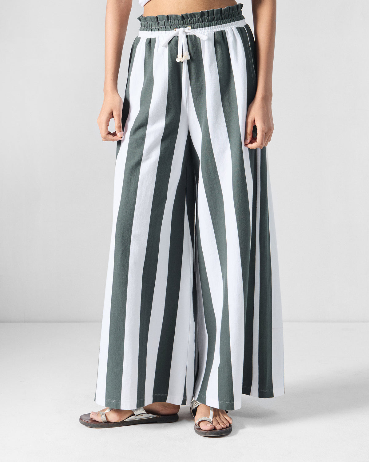 Person wearing charcoal and white striped Nova pants with a paperbag waist and drawstring.