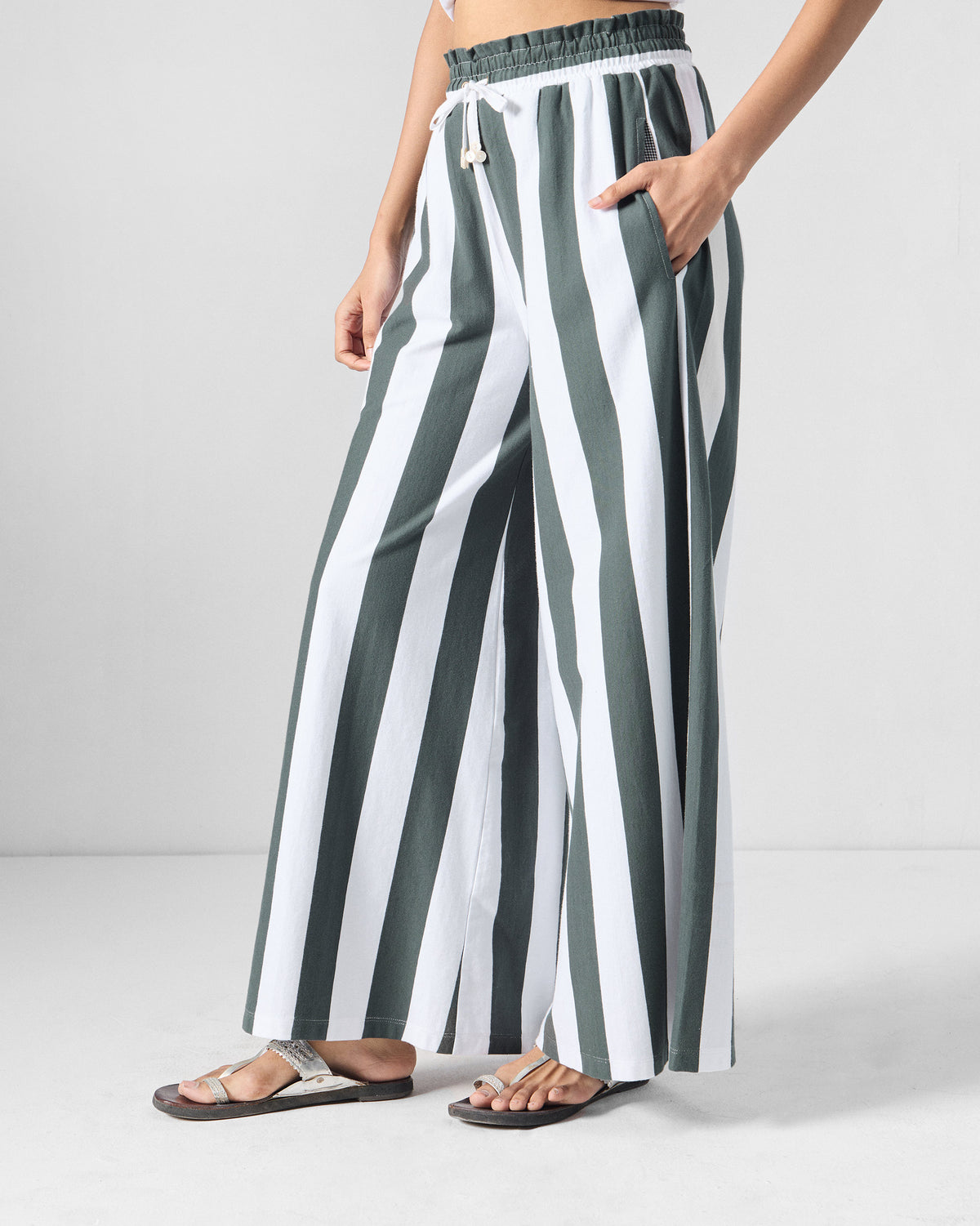 Side view of charcoal and white striped Nova pants showing the wide-leg drape.