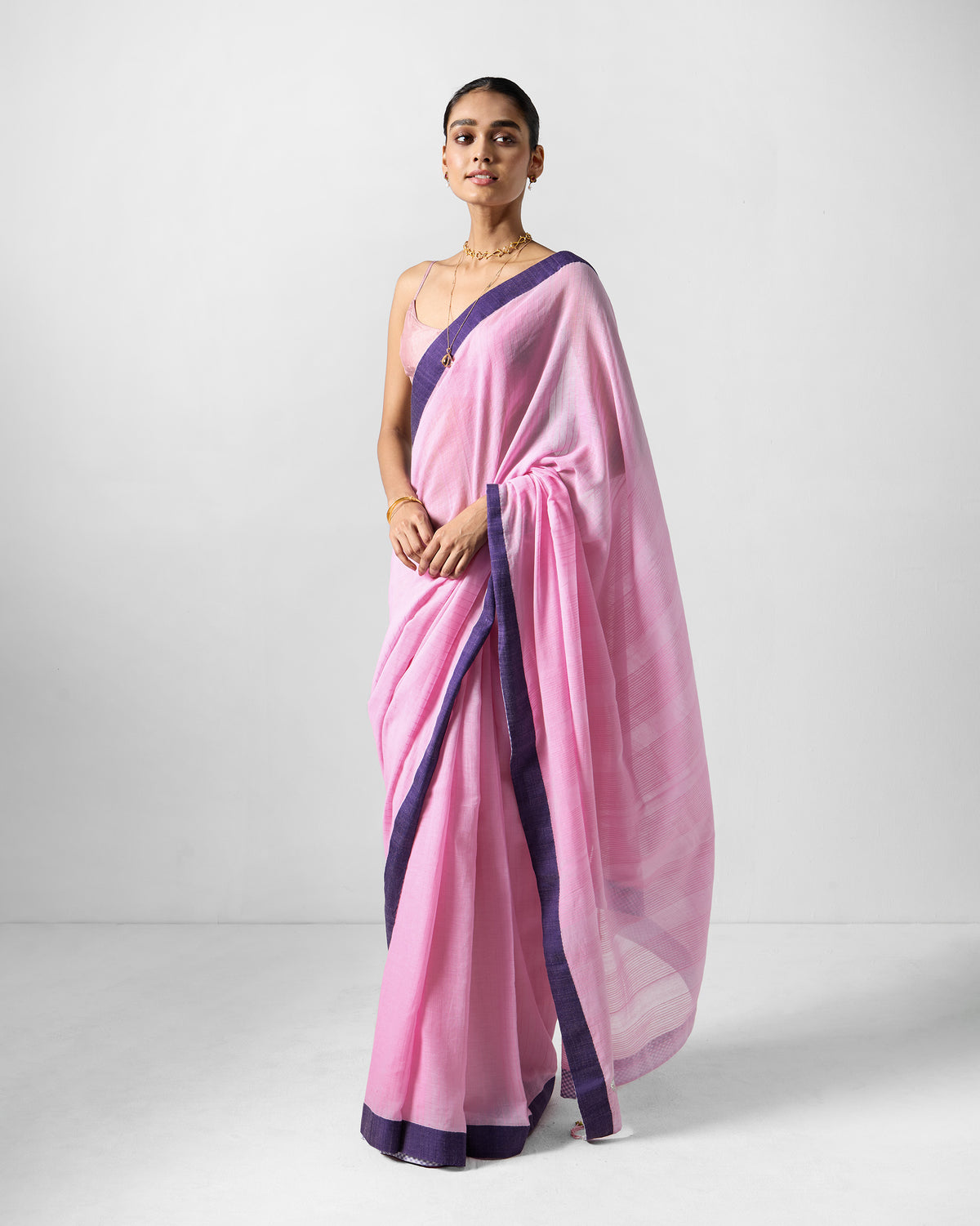 Person wearing a pink Noor sari with a purple border.