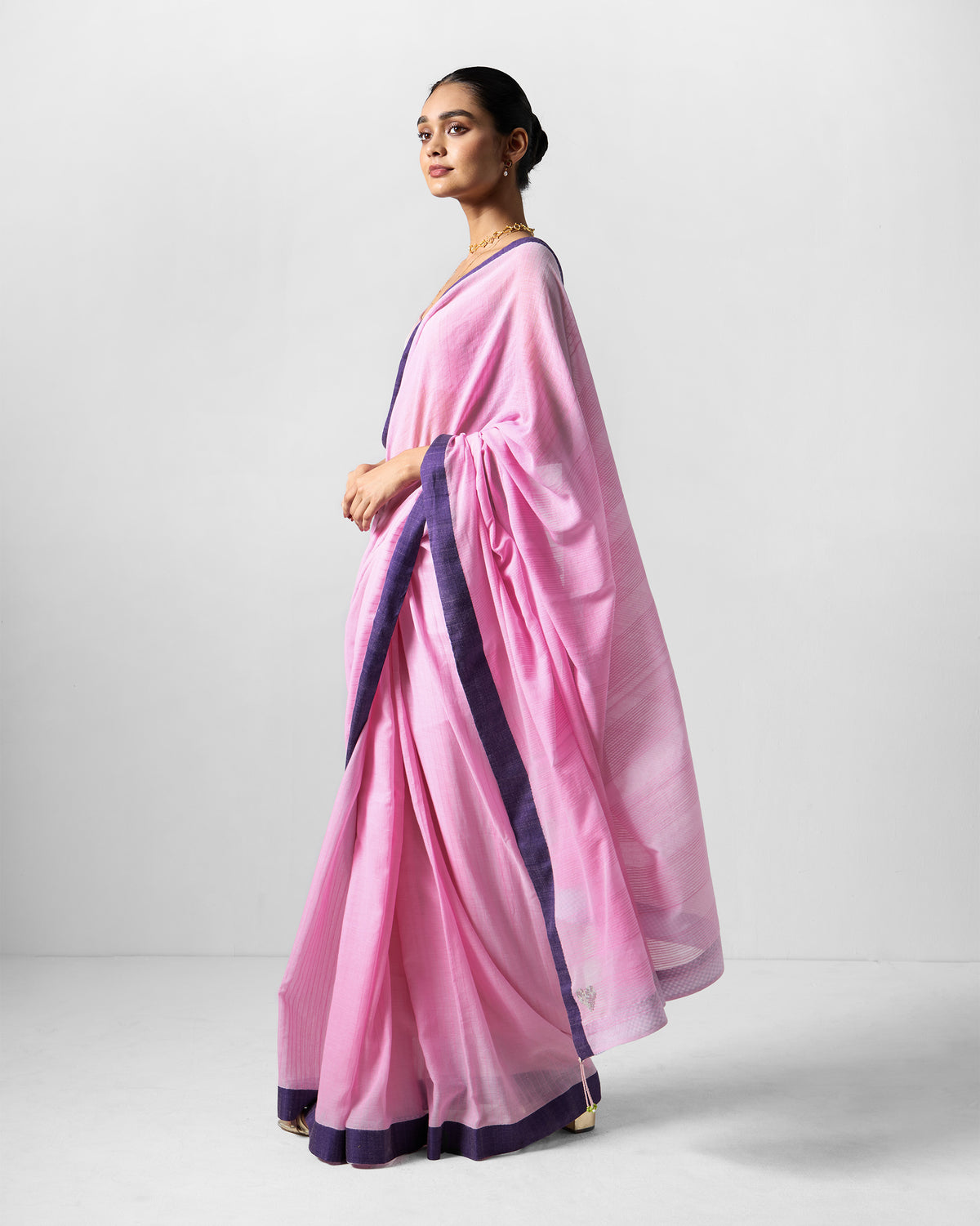 Side view of a pink Noor sari with a purple border.