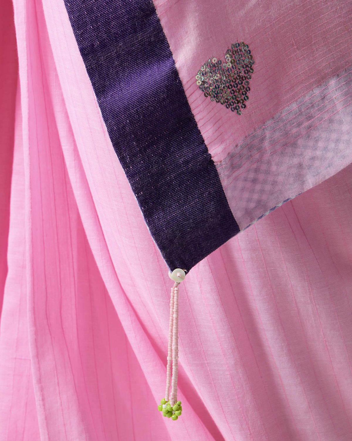 Close-up of pink Noor sari corner with a sequined heart and tassel.