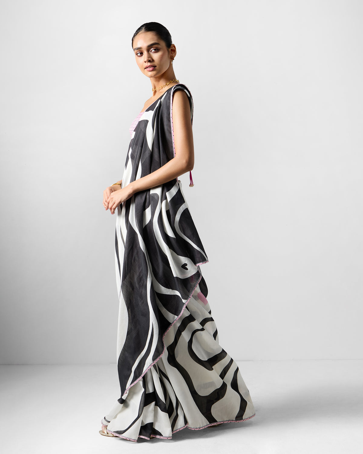 Side view of a white and black printed Ella sari with a pink border.