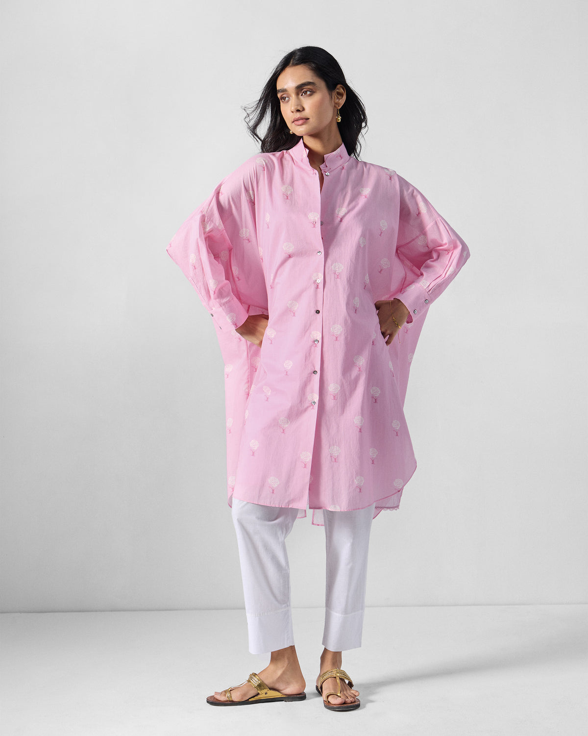 Person wearing a soft pink Raha tunic with a white rose print.