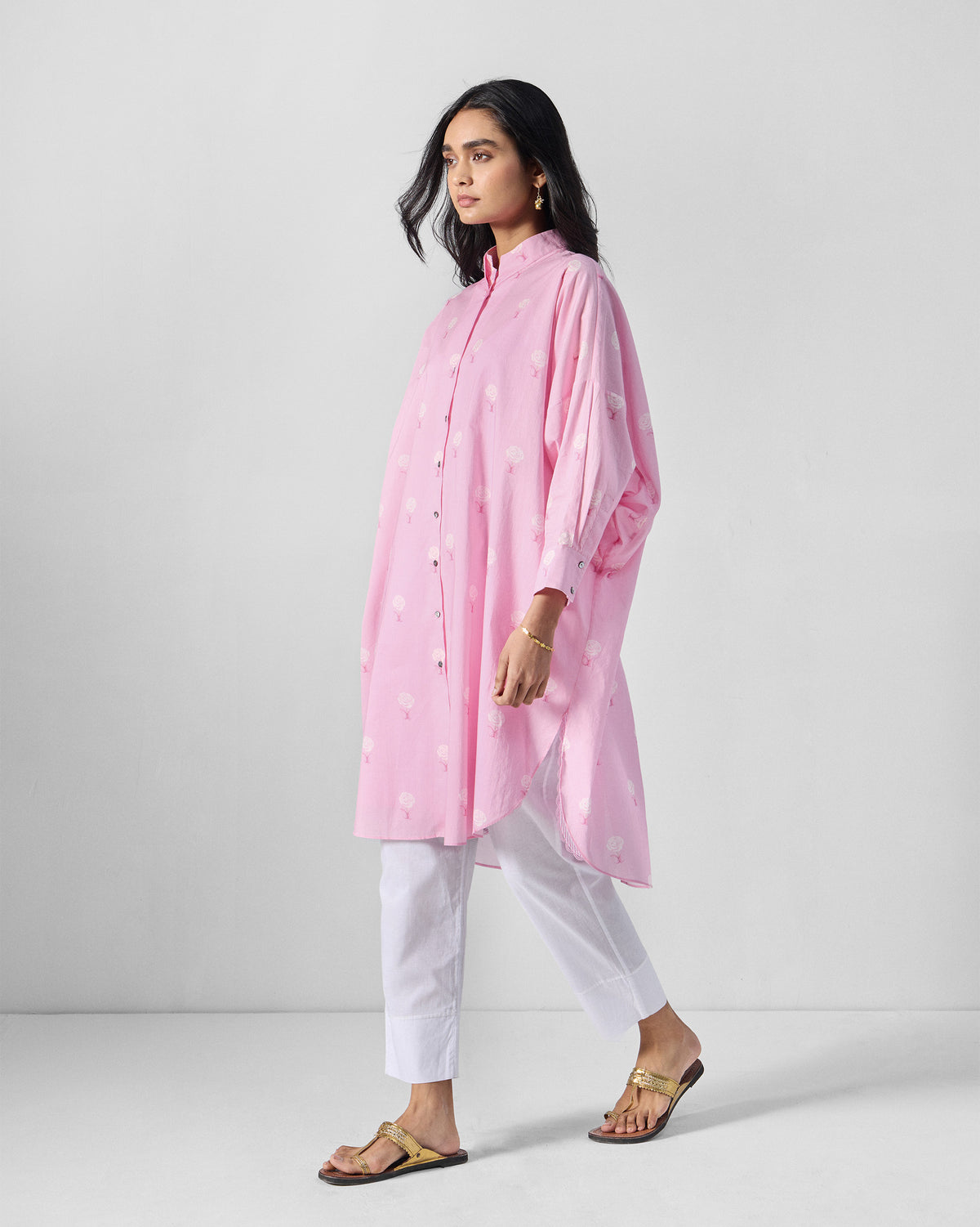 Person wearing a soft pink Raha tunic with a white rose print.