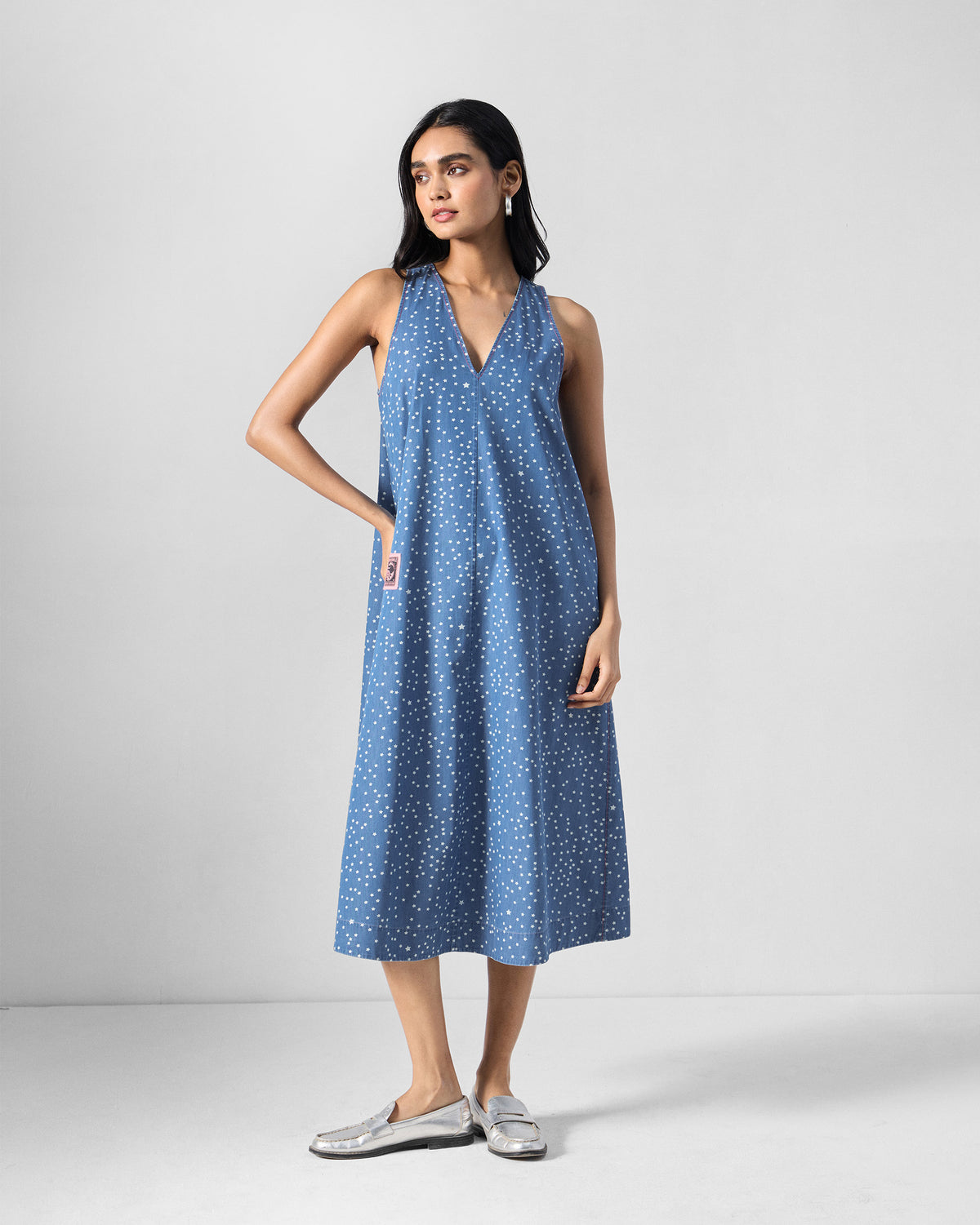 Person wearing a blue midi dress with a white star print.