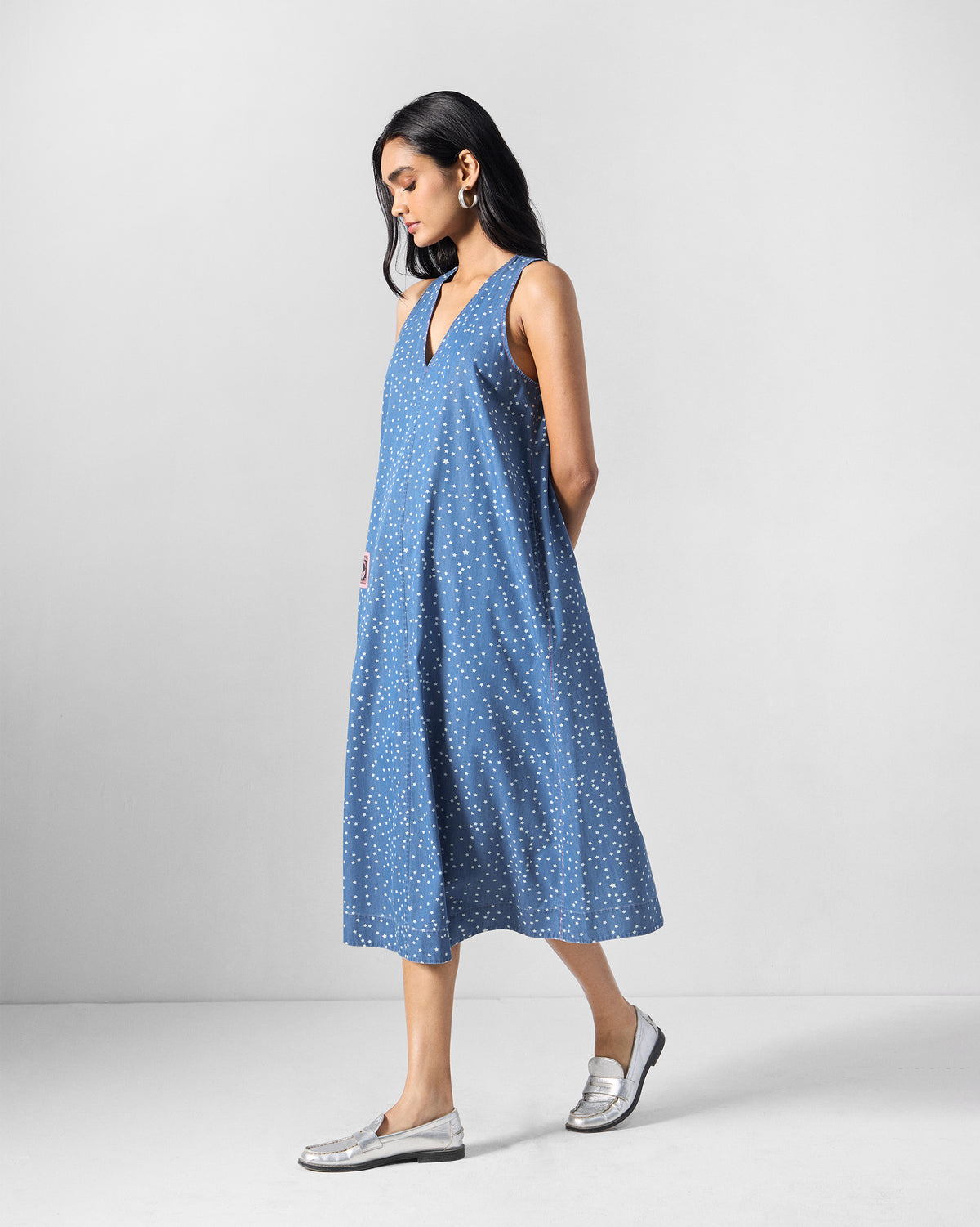 Person wearing a blue sleeveless midi dress with white stars.