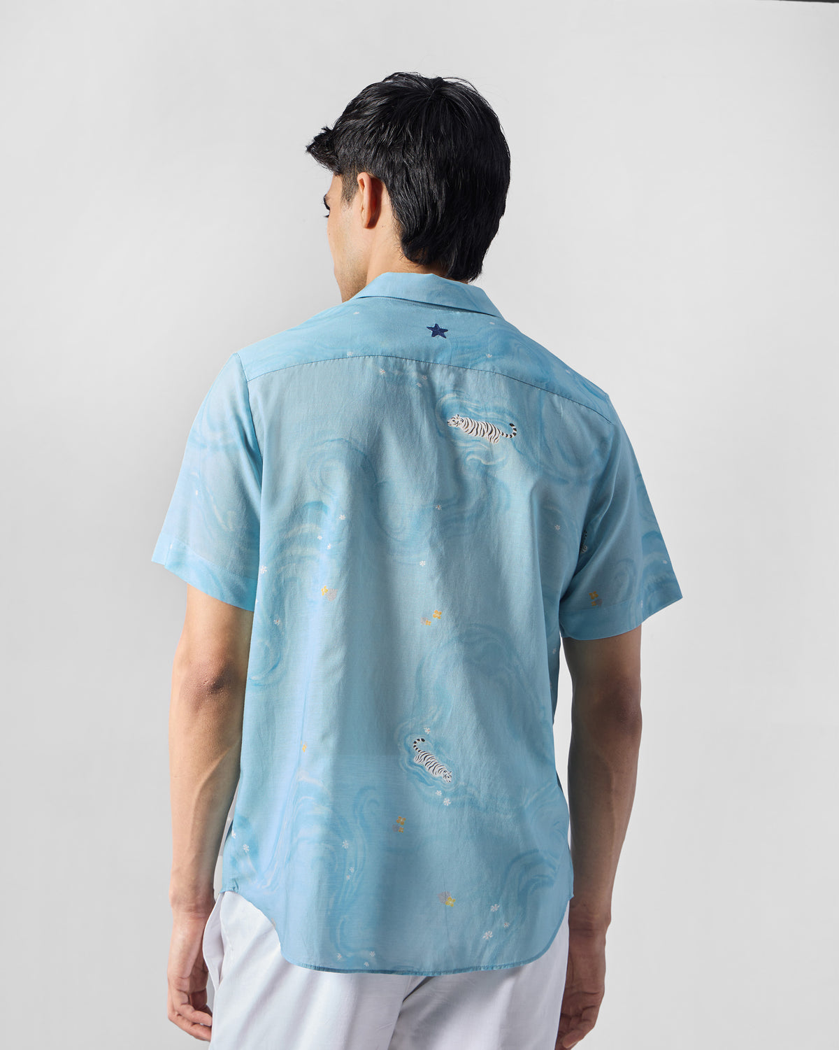 Back of a light blue printed Riverine shirt with tiger motifs.